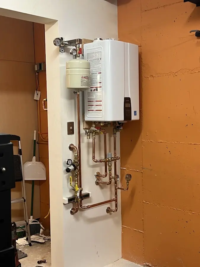 Plumbing technician inspecting water heater connections in Newington